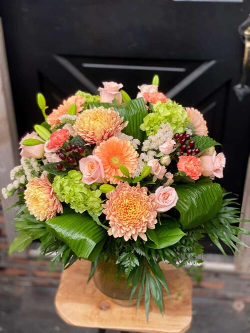 The Watering Can | A large orange and pink bouquet in a glass vase.