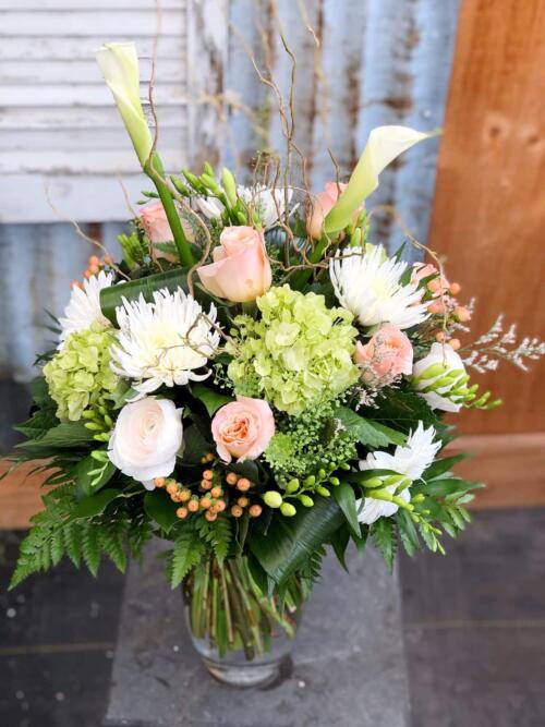 The Watering Can | A large peach and white bouqet in a tall glass vase.