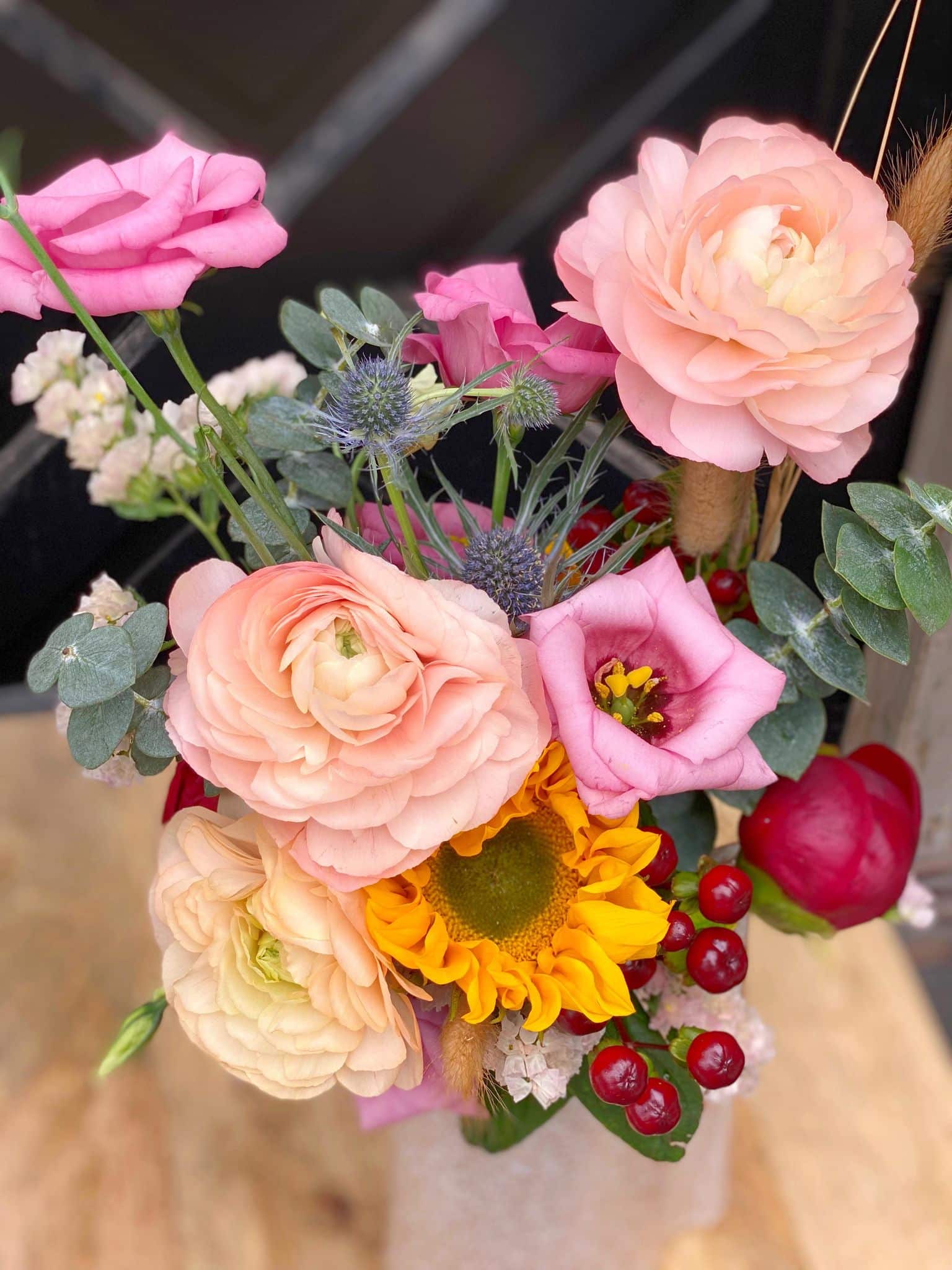 The Watering Can | Close up of the roses, rununculus, lisianthus, and sunflower in a summery bouquet.