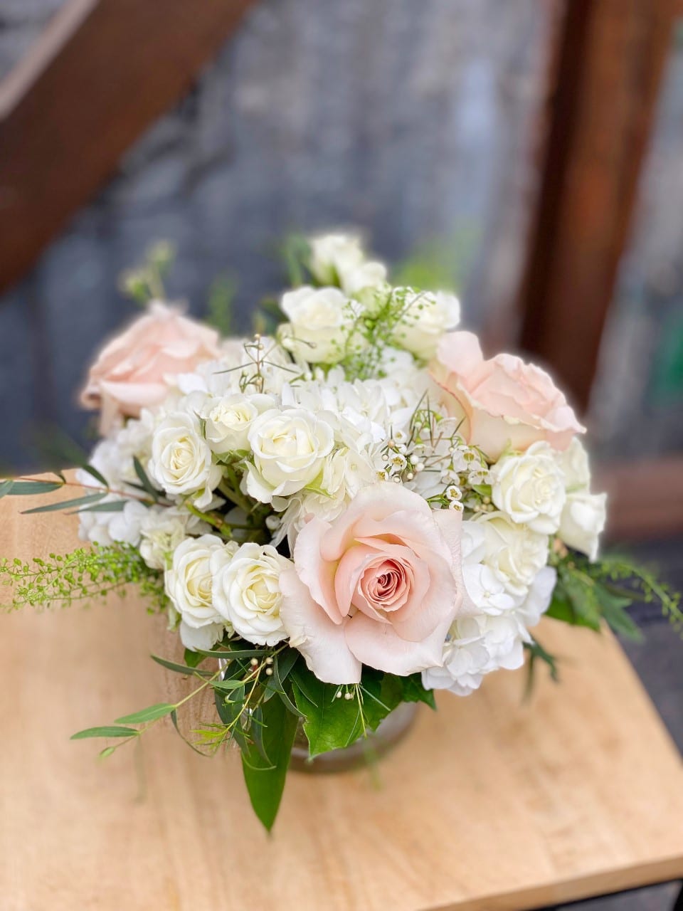 The Watering Can | A delicate white and blush pink posie style bouquet in a cylindrical glass vase.