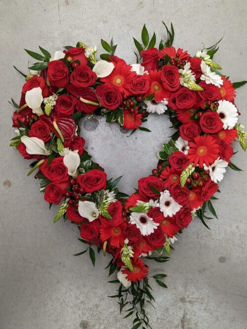 The Watering Can | A red and white hollow heart shaped floral piece made with red roses, red & white gerbera daisies, white calla lilies, burgundy hypericum, and star of Bethlehem with a sprinkling of greenery.