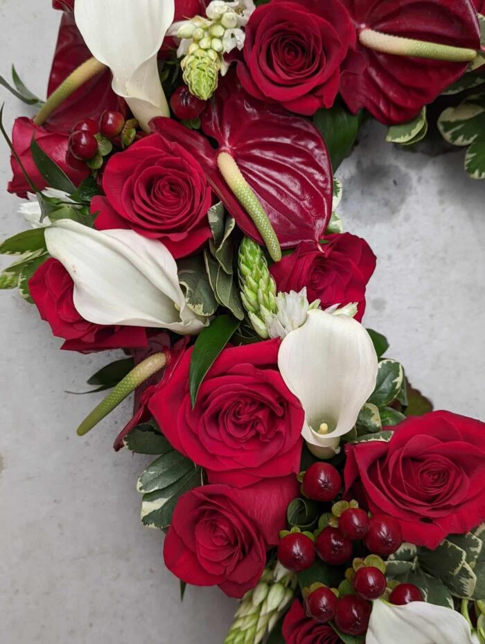 The Watering Can | Close up of roses, calla lilies, and anthuriums in a heart shaped floral arrangement.