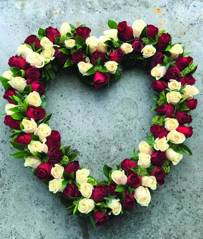 The Watering Can | A heart shaped outline full of red and white roses with some greenery.