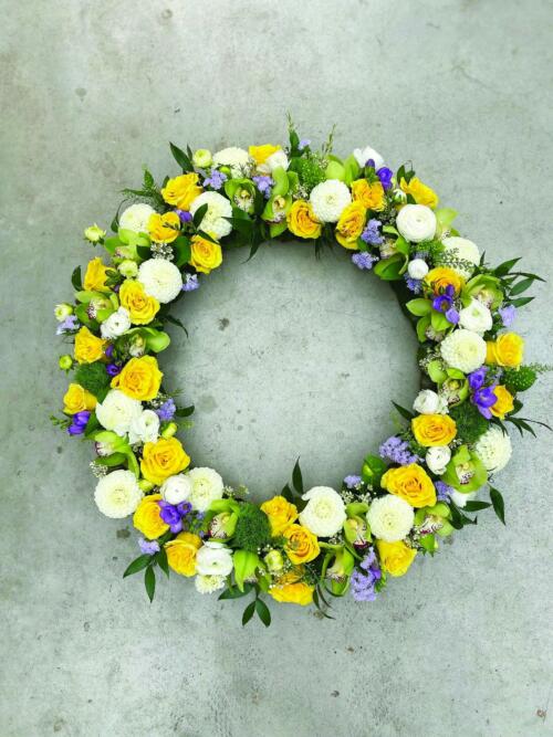 The Watering Can | A large yellow, white, and purple floral wreath.