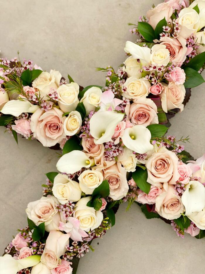 The Watering Can | Close up of the white calla lilies, white roses, blush spray roses, and pink cymbidium orchids in a floral cross.