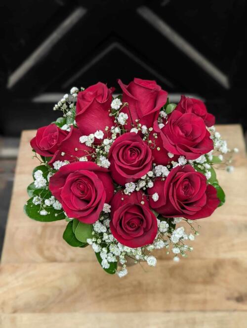 The Watering Can | A small bouquet of roses with baby's breath and minimal green wrapped with satin in a glass vase.