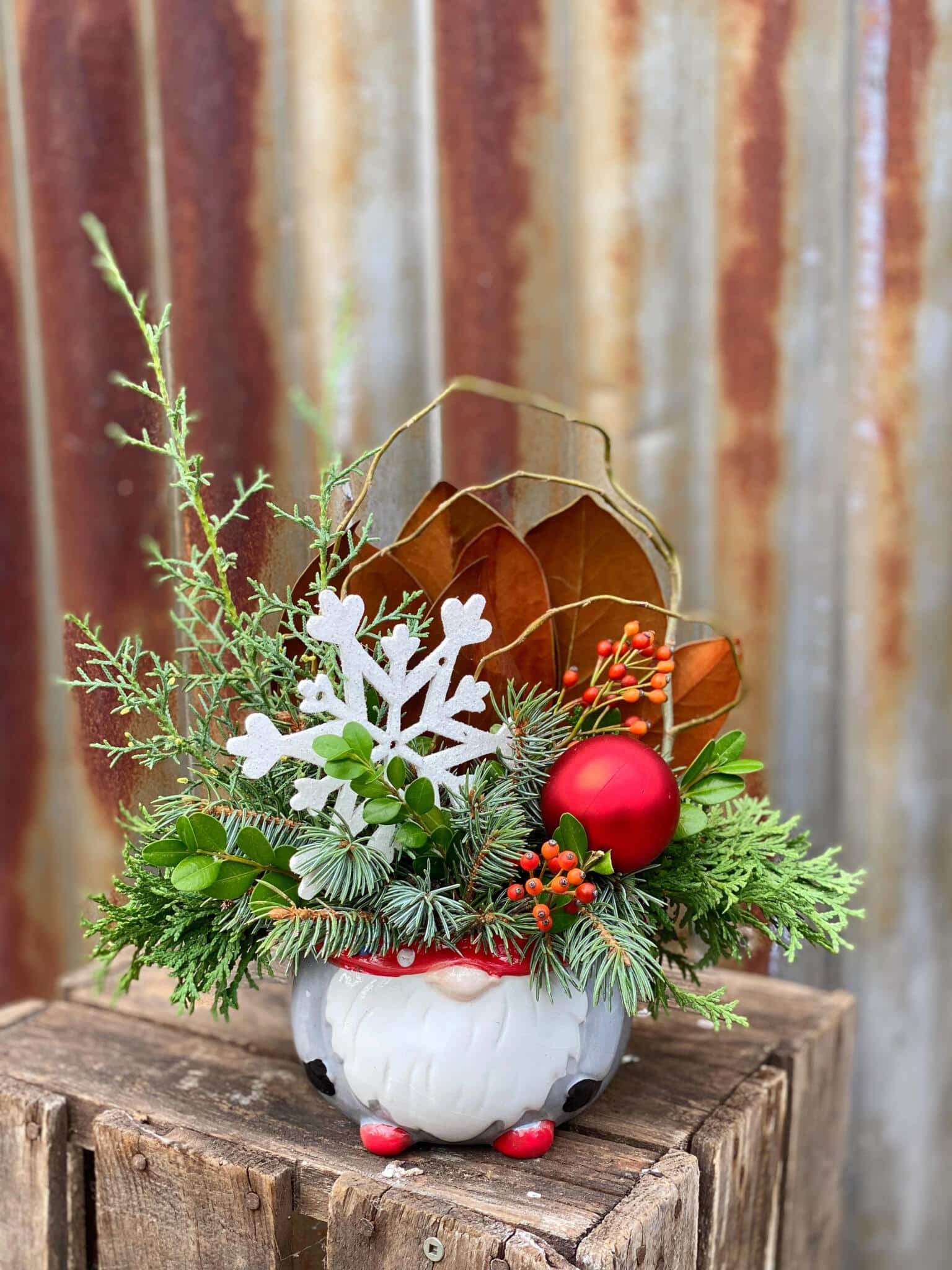 The Watering Can | A festive arrangement featuring a large white snowflake in a gnome shaped container.
