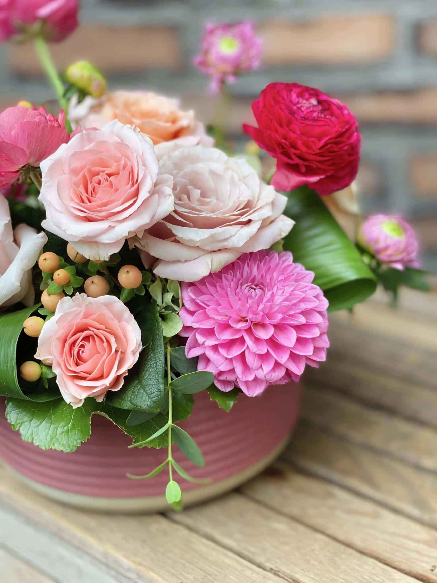 The Watering Can | Pink dahlia, soft pink roses,, and hot pink ranunculus in an European style floral arrangement.