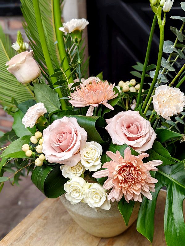 The Watering Can | Blush mums, quicksand roses, white spray roses, and blush carnations in a European style floral arrangement.